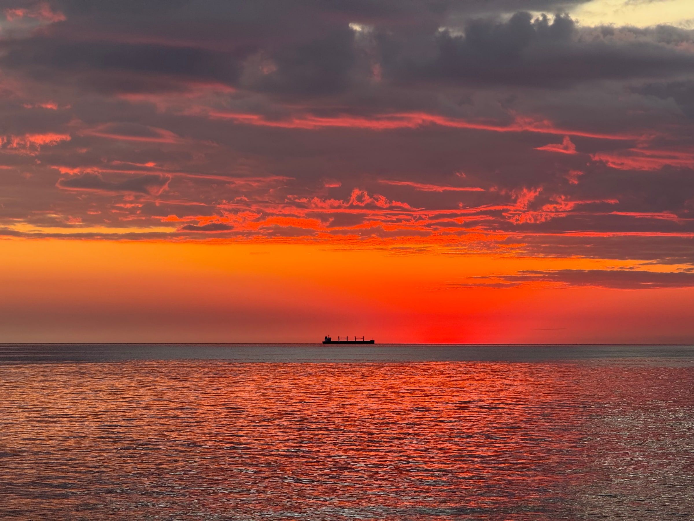Atardecer naranja sobre el Río de la Plata en Colonia, con un barco en el horizonte